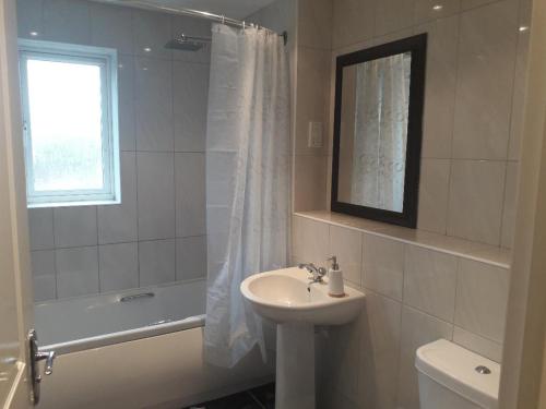 a white bathroom with a sink and a bath tub and a sink at Greenock Home Stay in Wolverhampton