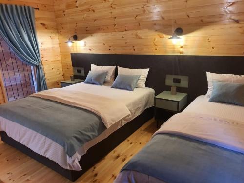two beds in a room with wooden walls at Enjoy river house Ada Bojana in Ulcinj
