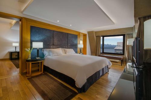 ein Schlafzimmer mit einem großen Bett und einem großen Fenster in der Unterkunft NH Bariloche Edelweiss in San Carlos de Bariloche