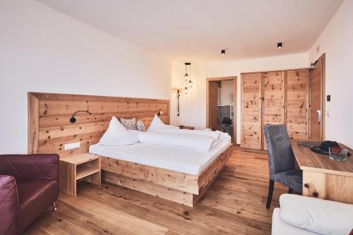 a bedroom with a large bed with a wooden wall at Hotel Kristall in Maranza