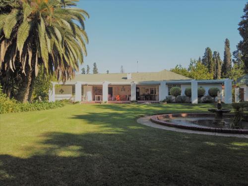 a house with a palm tree and a fountain at Happy Lands Farmstay in Addo