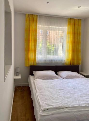 a bedroom with a bed and a window with yellow curtains at Pokoje u Jarka in Krzyżowa