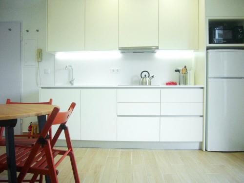 a kitchen with white cabinets and a table and a refrigerator at Castle, Terrace and Relax in Tomar