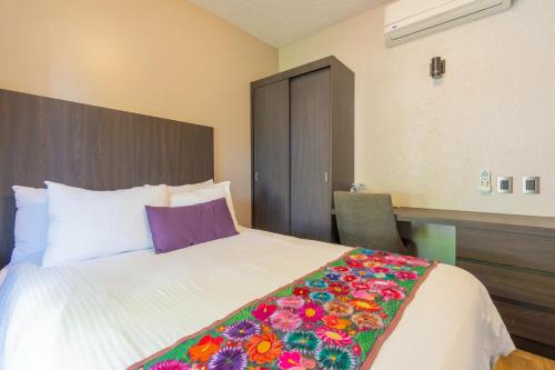 a bedroom with a large white bed with a colorful blanket at Hotel Flamingo Inn in Querétaro