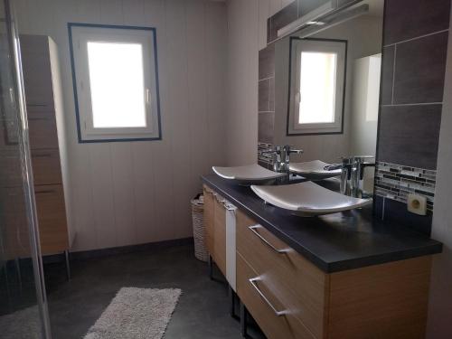 a bathroom with two sinks and two mirrors at Maison individuelle in Brette-les-Pins