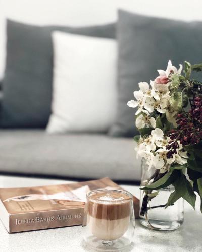Mavrovo Twins Apartment في مافروفو: طاولة مع إناء من الزهور وكوب من القهوة