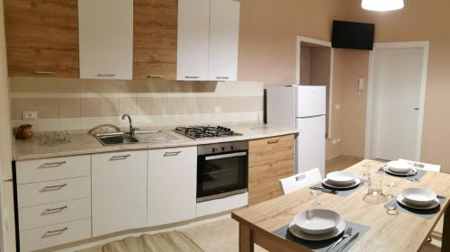 a kitchen with white cabinets and a table with plates on it at Cuore di Conchiglia in Custonaci