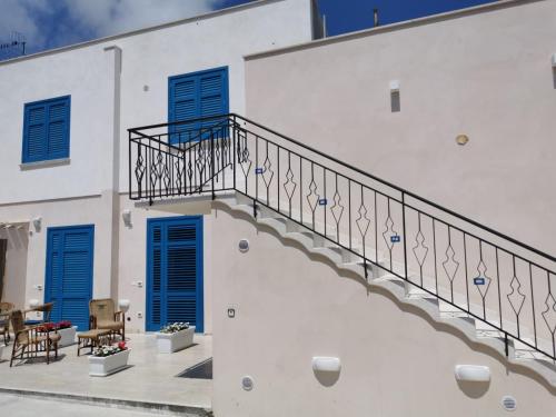 a white building with blue shutters and stairs at Cuore di Conchiglia in Custonaci