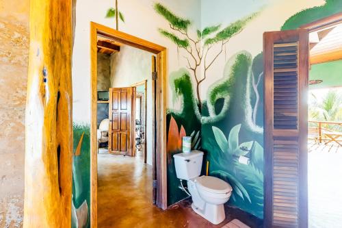 baño con aseo y una pintura en la pared en La Casa Pura Vida, en San Pedro