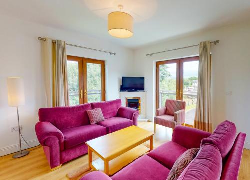 a living room with purple couches and a tv at Lakeside Holiday Homes - Type A by Trident Holiday Homes in Killaloe