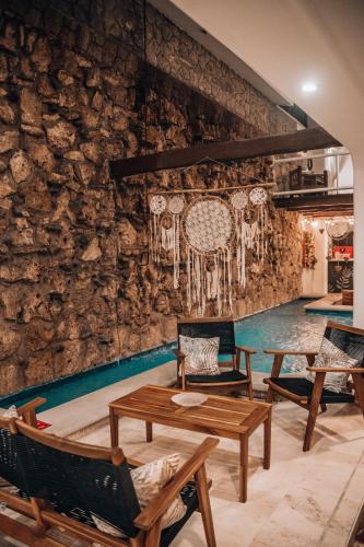 a room with chairs and tables and a stone wall at Ahava Hotel in Playa del Carmen