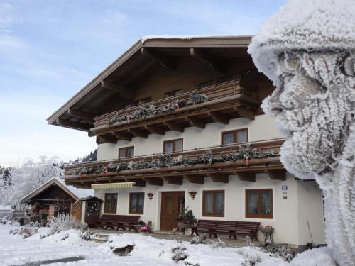 a building in the snow with benches in front at Pension Forsthof in Maishofen
