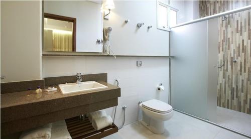 a bathroom with a toilet and a sink and a shower at Lirio D'Água Hotel in Olímpia