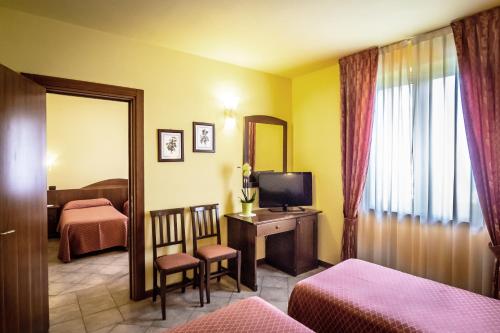 um quarto de hotel com um quarto com uma televisão e um espelho em Hotel Al Poggio Verde em Barghe