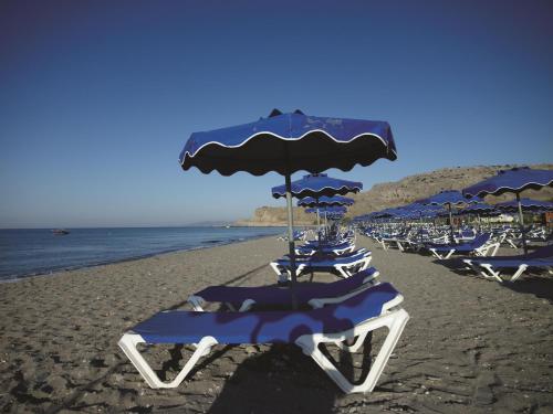 a group of chairs and umbrellas on a beach at Lindos Princess Beach Hotel in Lardos