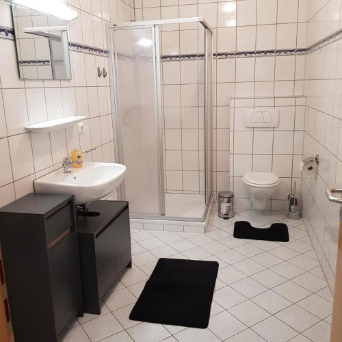 a bathroom with a sink and a shower and a toilet at Gasthaus Kristall 2 in Salzwedel