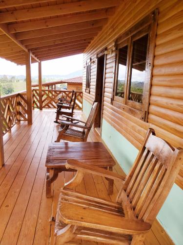 a porch with wooden chairs and a table on a cabin at Villas Las Neblinas in Constanza