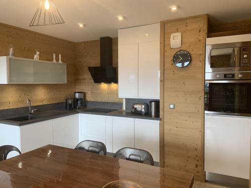 土绪尔ODYSSEE D103 Appartement chaleureux sur les pistes的配有白色橱柜、桌子和椅子的厨房