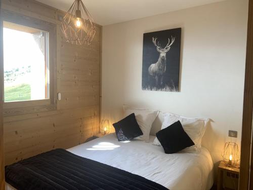 a bedroom with a bed with a deer picture on the wall at ODYSSEE D103 Appartement chaleureux sur les pistes in La Toussuire