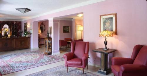 a living room with two red chairs and a table at Hotel Monna Lisa in Vinci