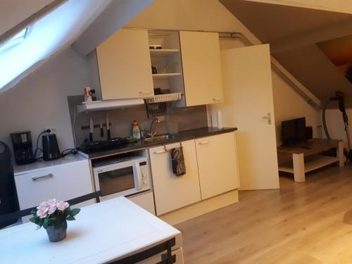 - une cuisine avec des placards blancs et une table dans une pièce dans l'établissement Studio vlak bij het strand, à Petten