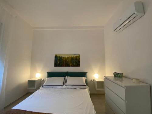 a white bedroom with a bed and two lights at Riviera Apartments in Pescara