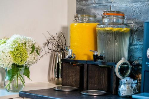 a counter with two jars of orange juice and a vase of flowers at Národní dům Podbořany in Podbořany