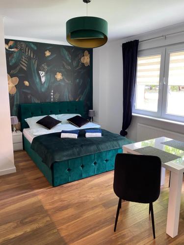 a bedroom with a green bed and a table at Apartament MATEO in Malbork