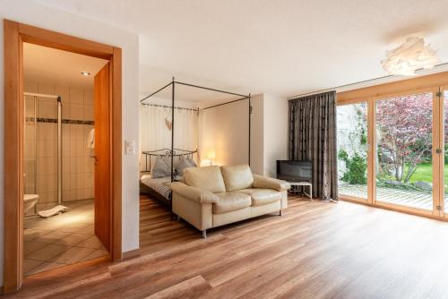 a bedroom with a bed and a couch and a television at Haus Alpine in Zermatt