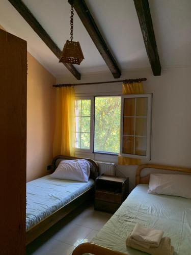 1 dormitorio con 2 camas y ventana en Villa Riverside, en Platána