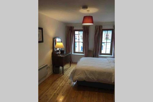 a bedroom with a bed and a desk and two windows at Apartment 4, Clifden Bay Apartments in Clifden
