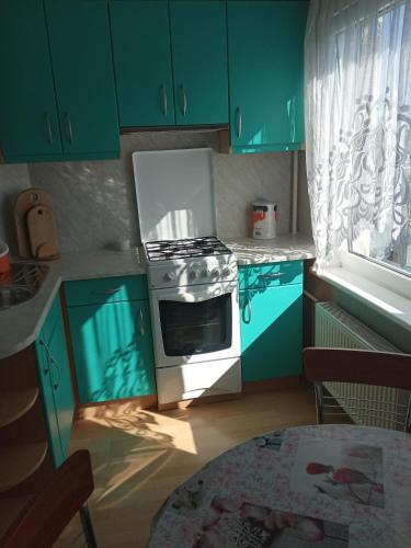 a kitchen with green cabinets and a stove and a table at Saules House in Ventspils