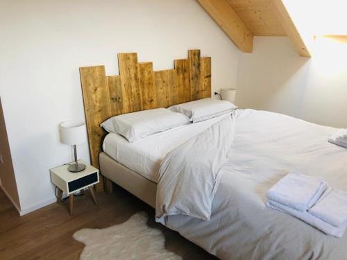 a bedroom with a large white bed with a wooden headboard at Piano C Apartment in Cavalese