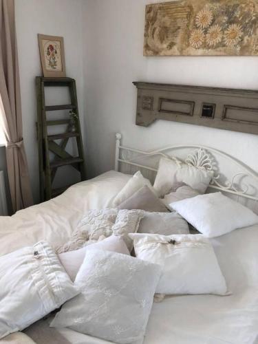 Una cama con sábanas blancas y almohadas. en Tina Risager bed & breakfast, en Sindal