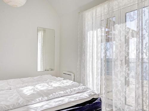a white bedroom with a bed and a window at Three-Bedroom Holiday home in Gørlev 7 in Rønne