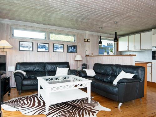 a living room with a black leather couch and a table at 6 person holiday home in Knebel in Knebel