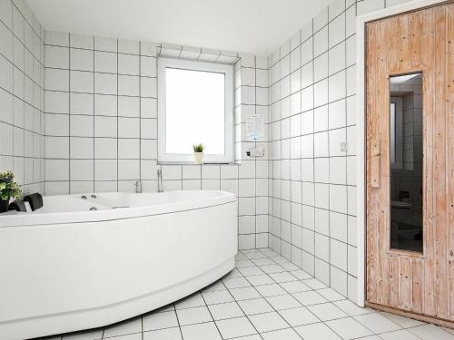 een witte badkamer met een bad en een raam bij 10 person holiday home in L kken in Løkken