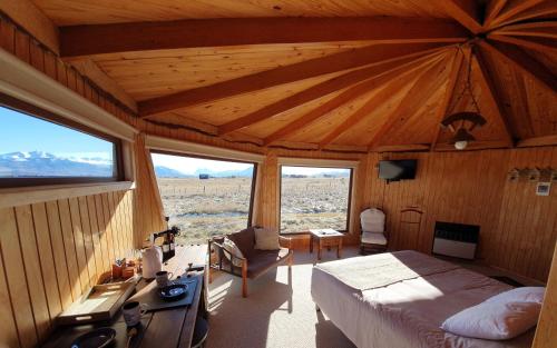 um quarto com uma cama num quarto com janelas em Cabañas y Casa Kauken em Puerto Natales