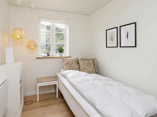 ブロックフスにあるHoliday home Blokhus VIIの白いベッドルーム(ベッド1台、椅子付)