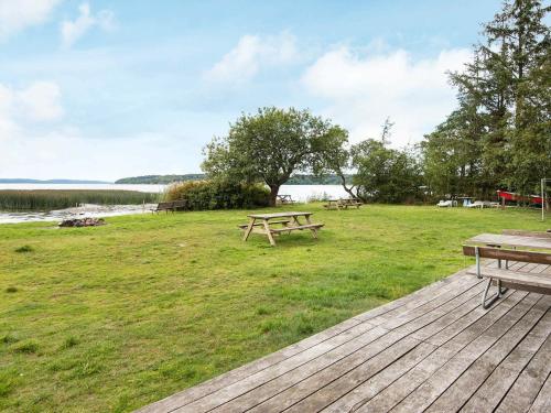 a picnic table and benches on a deck near the water at Lakefront Retreat in Sohojlandet - By Traum Ferienwohnungen in Skanderborg