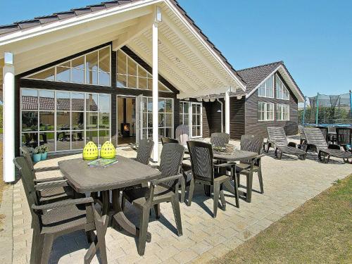 een patio met een tafel en stoelen en een huis bij 14 person holiday home in Odder in Odder
