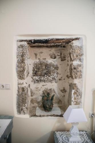 a stone wall with a vase on a table with a lamp at Chalkidιό in Pitsidia