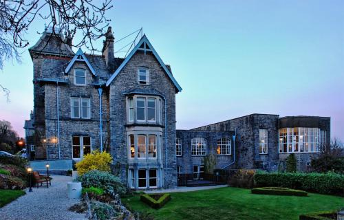 an old stone house with a garden in front of it at Cumbria Grand Hotel in Grange Over Sands