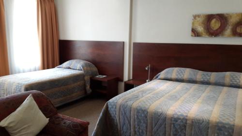 a hotel room with two beds and a chair at The Shakespeare Inn in Vanderbijlpark