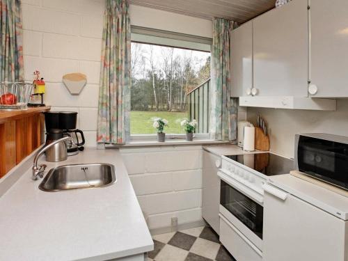 a white kitchen with a sink and a window at 4 person holiday home in L s in Læsø