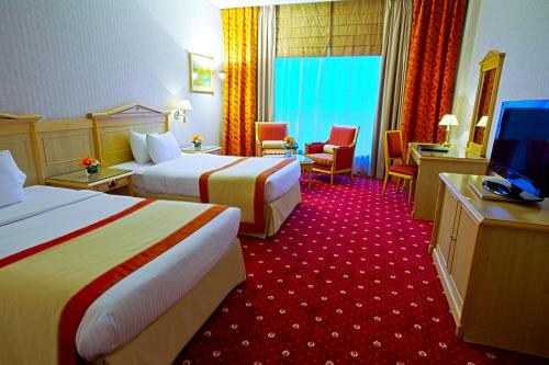 a hotel room with two beds and a flat screen tv at Capitol Hotel Jumeirah Dubai in Dubai