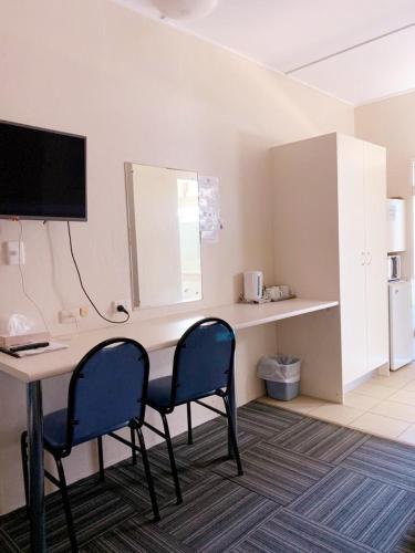 a room with a desk with two chairs and a television at Walgett Motel in Walgett