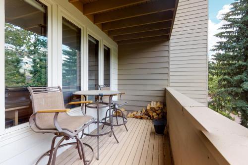 a porch with three chairs and a table on it at Sun Vail 24A in Vail