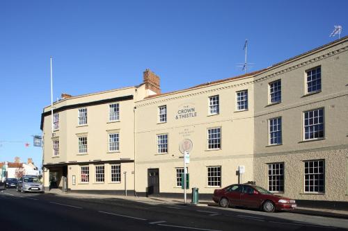 un coche rojo estacionado frente a un gran edificio en The Crown And Thistle en Abingdon