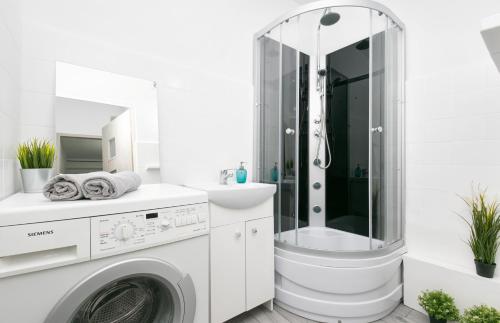 a white bathroom with a washing machine and a shower at Rooms4Less in Gdańsk